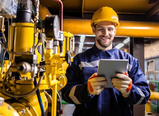 Engineer standing by natural gas installations and pipeline checking consumption on tablet computer application