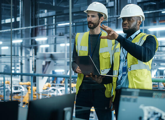 Project manager and automotive engineer in hard hat at car factory