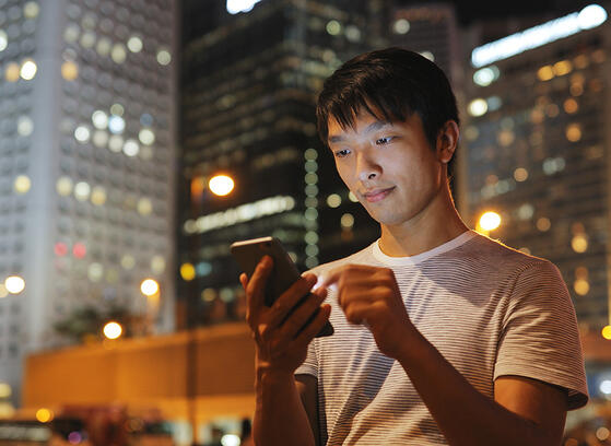 Young Asian man using mobile phone in city at night