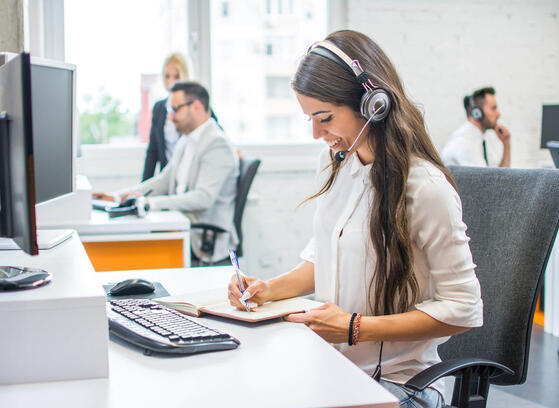 Woman working at business contact center, talking on the phone with headset
