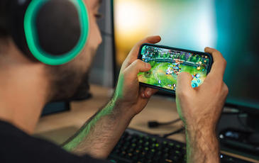 Man playing a game on mobile phone wearing headphones
