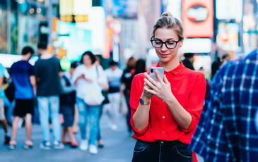 Woman on a busy street looking at her phone