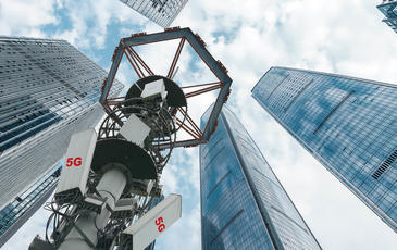 Low angle view of 5G antenna with modern skyscrapers and financial buildings