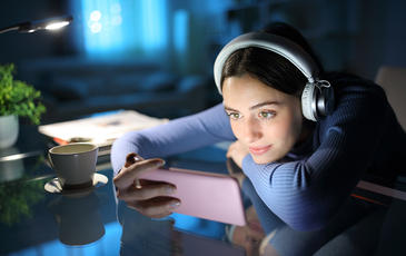 Woman watching media on smartphone in the night at home