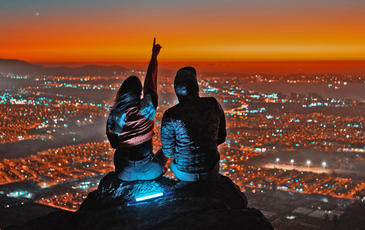 Couple overlooking the city. Night time with dramatic landscape