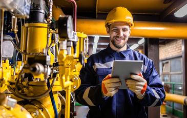 Engineer standing by natural gas installations and pipeline checking consumption on tablet computer application