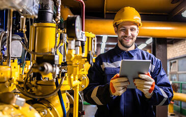 Engineer standing by natural gas installations and pipeline checking consumption on tablet computer application