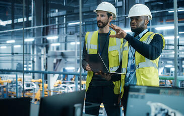 Project manager and automotive engineer in hard hat at car factory