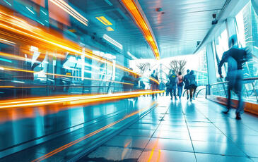 A busy city street with people walking, and a train passing in the background.