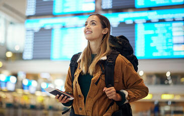 Woman with backpack at the airport holding travel ticket and documents