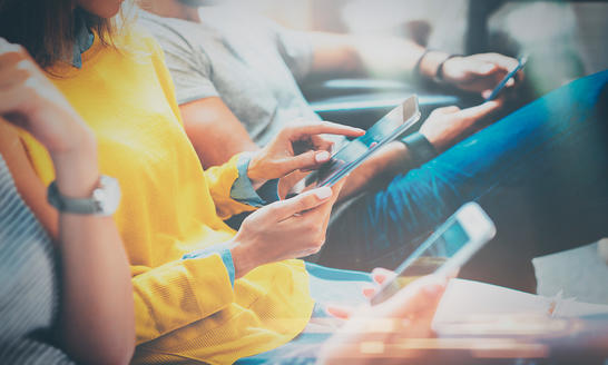 People sitting on a couch with phones