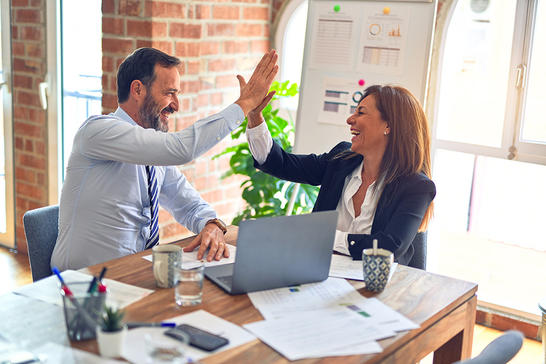 Man and woman in the office, clapping hands in victory