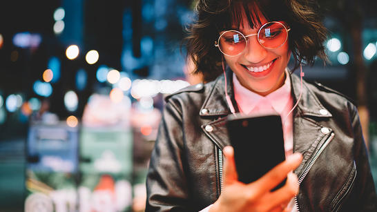Happy female having a video call with headphones at night