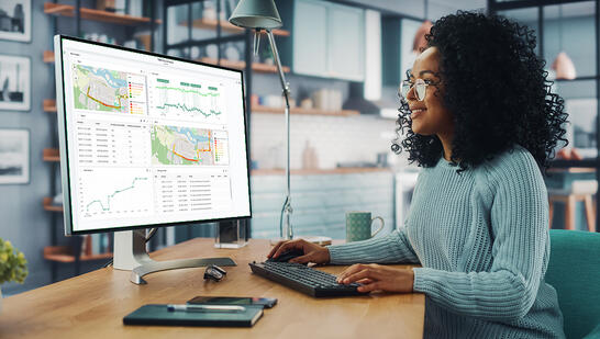 Woman working from home office reviewing a TEMS Cloud analytics report on her desktop screen