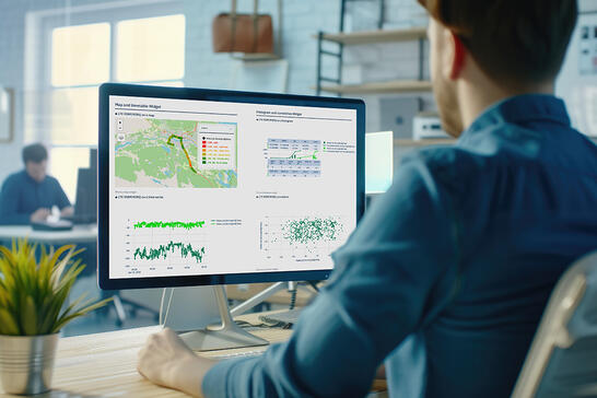Man viewed from behind analyzing a network testing analytics report on the TEMS Cloud dashboard