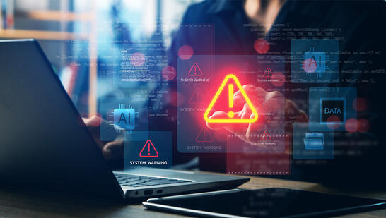 Laptop with a glowing warning icon over flowing network data, representing VistAI monitoring RAN, Core, and Transport health.