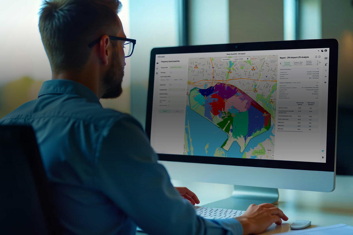 Man in office viewing a Planet Cloud report on a computer monitor—co-developed with Google Cloud for 4G and 5G network planning and optimization.