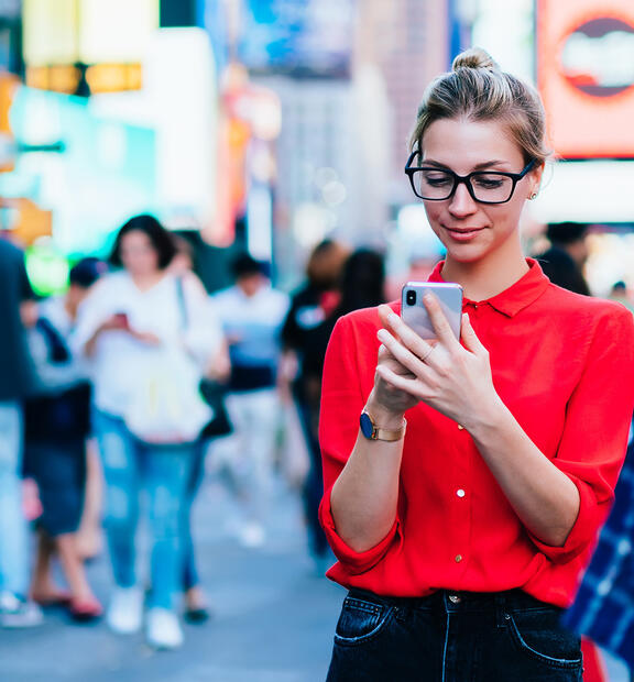 Woman on a busy street looking at her phone