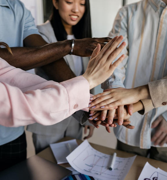 Group of colleagues showing support by holding hands together
