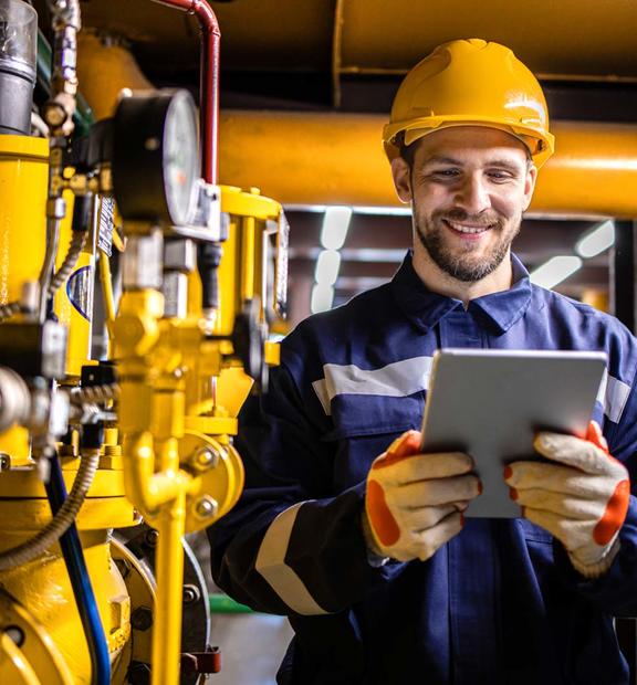 Engineer standing by natural gas installations and pipeline checking consumption on tablet computer application