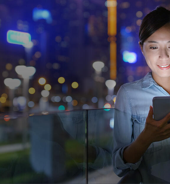 Woman looking at her phone in a dense city at night