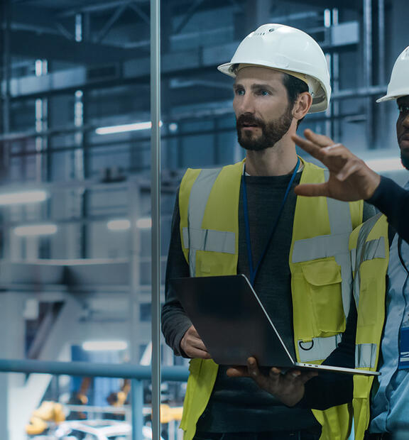 Project manager and automotive engineer in hard hat at car factory