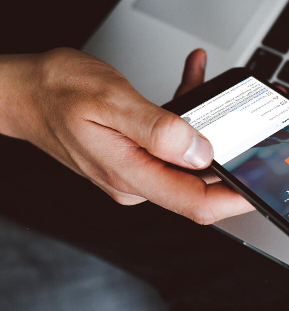 Hand holding mobile device with Infovista newsletter for up-to-date technology news
