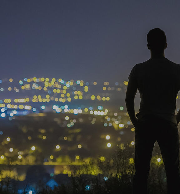 Man standing overlooking city at nighttime 