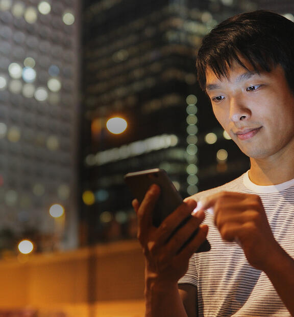 Young Asian man using mobile phone in city at night
