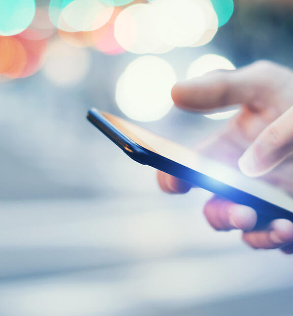 Closeup of hand holding mobile phone at night in city environment