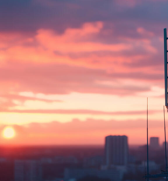 5G communication tower at sunset overlooking cityscape