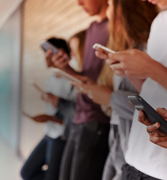 Team of collage students with mobile phones standing in a corridor