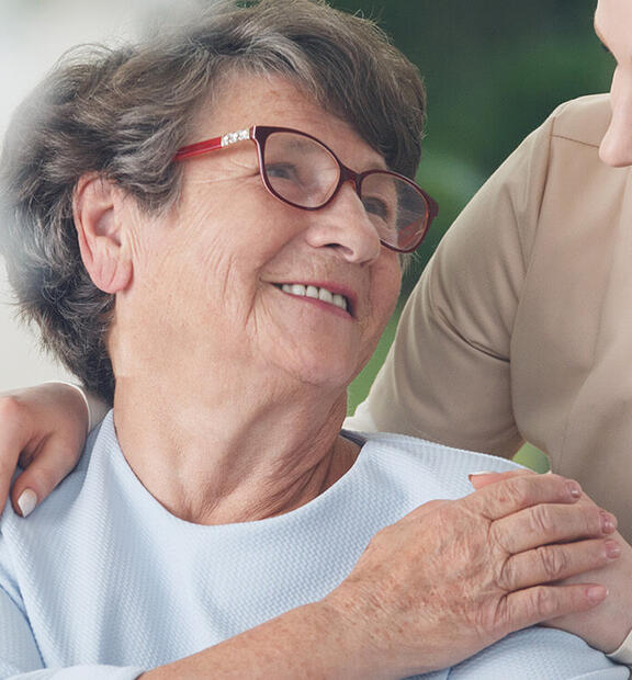 Smiling caregiver chatting with a senior woman in a joyful healthcare setting.