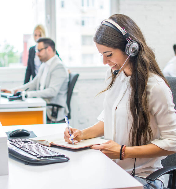 Woman working at business contact center, talking on the phone with headset