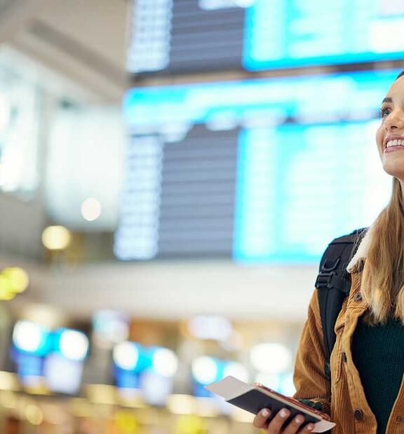 Woman with backpack at the airport holding travel ticket and documents