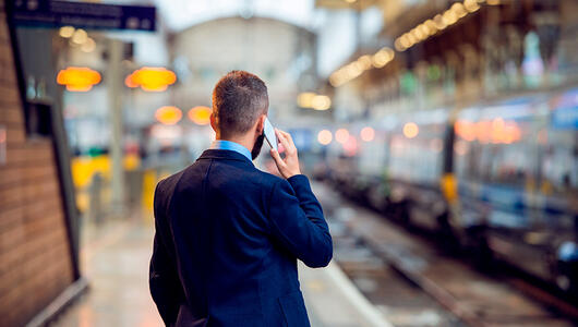 Man at train station talking on the phone