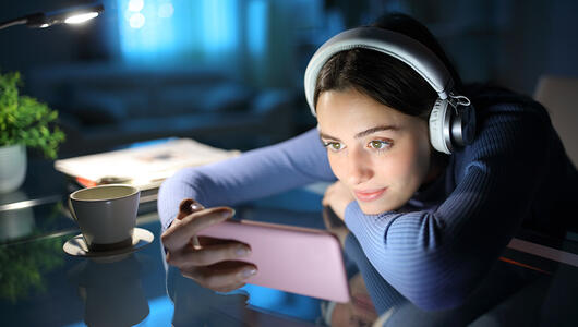 Woman watching media on smartphone in the night at home