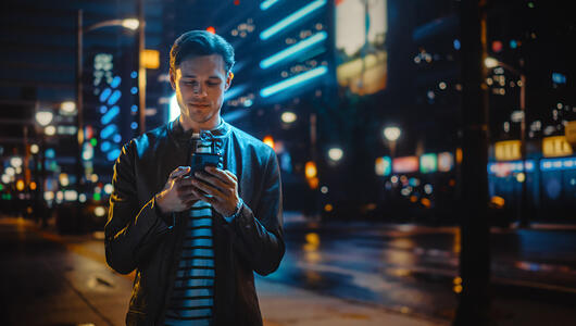 Man looking at his mobile phone in a dark urban city