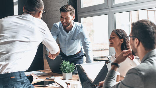 Partners shaking hands in meeting room