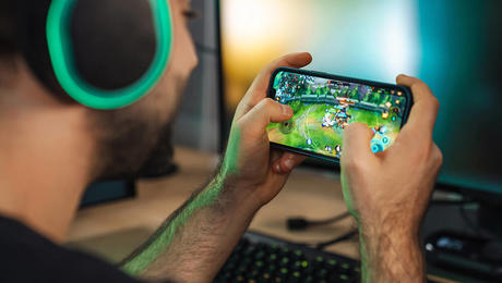 Man playing a game on mobile phone wearing headphones