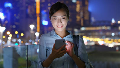 Happy Asian woman using voice, data and OTT services outdoor in a big city