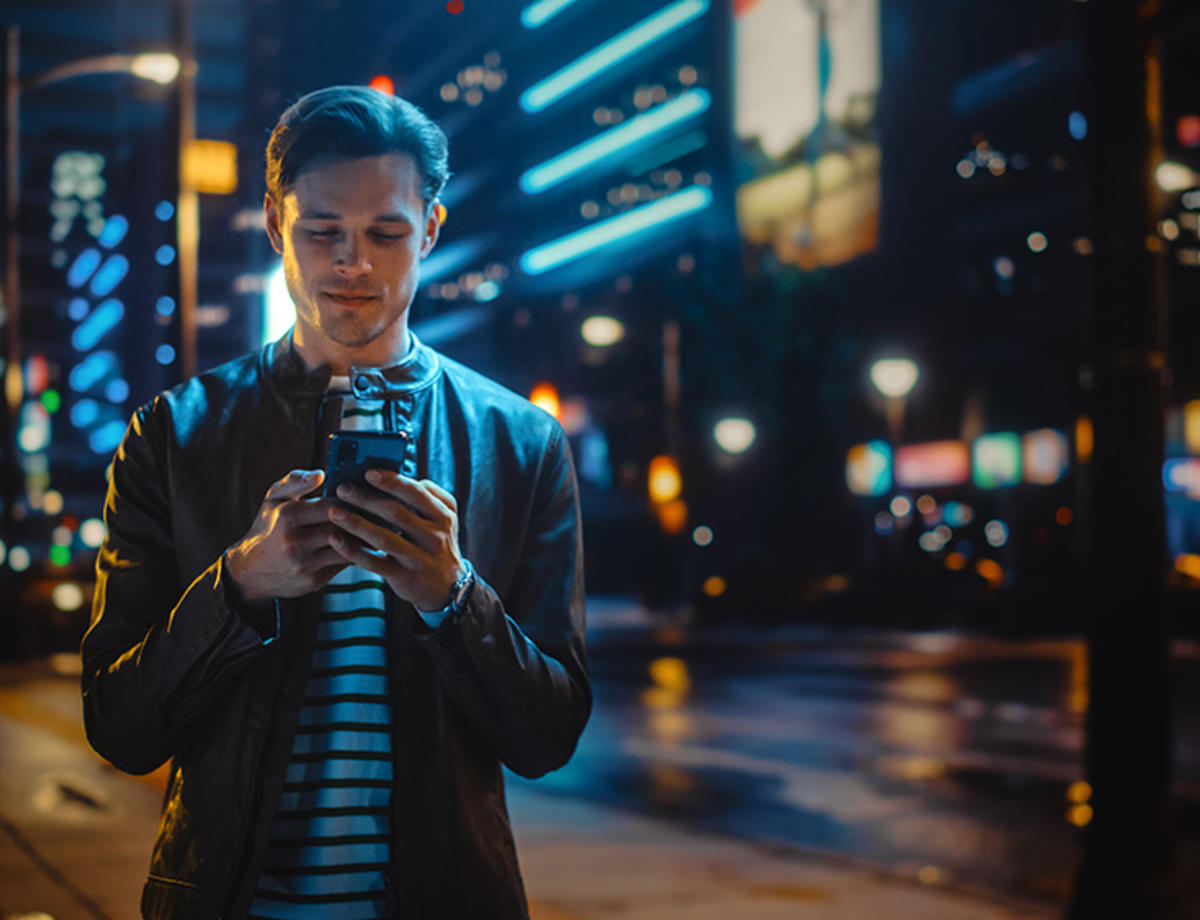 Man in the city looking at his phone at night