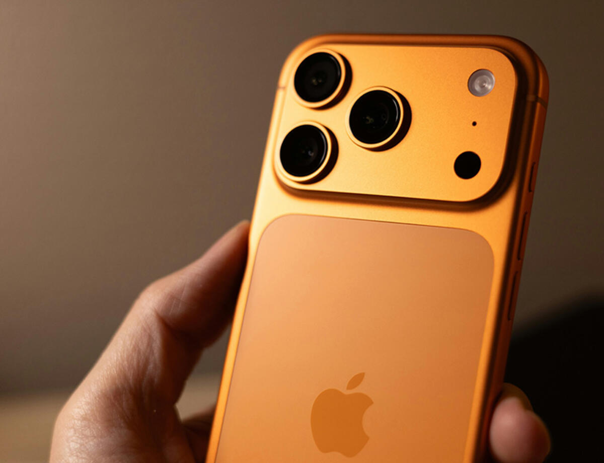 Hand holding the new iPhone 17 Pro in Cosmic Orange